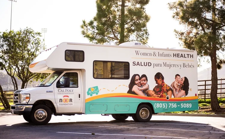 Van serving as a mobile health unit with images of women holding their children printed on the side and the SLO Noor Foundation logo.