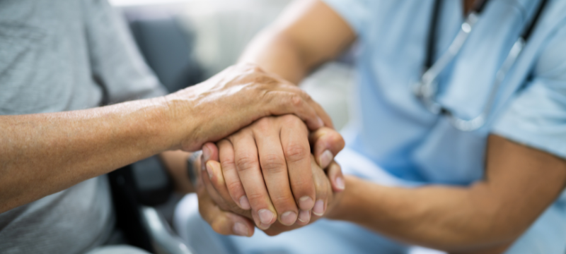 A health care worker holding the hands of a patient.