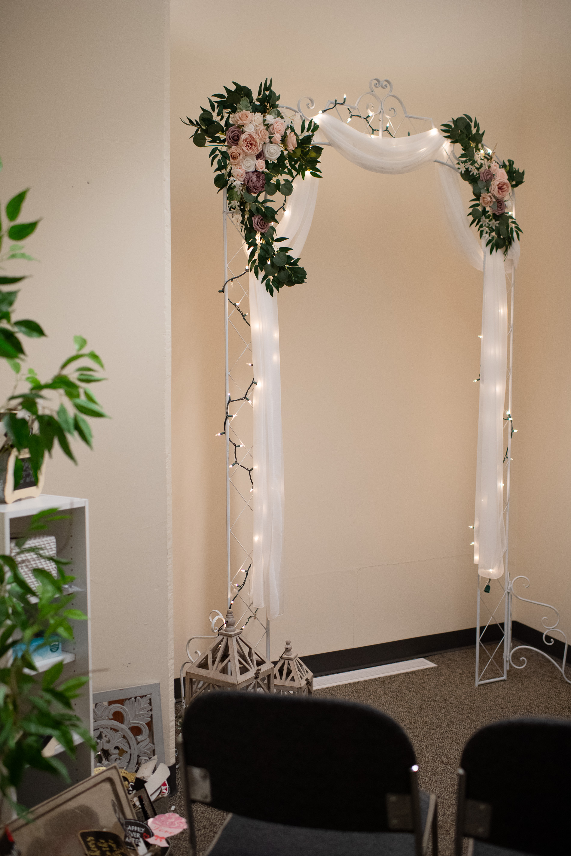 a decorative arch covered with fabric, lights, and flowers