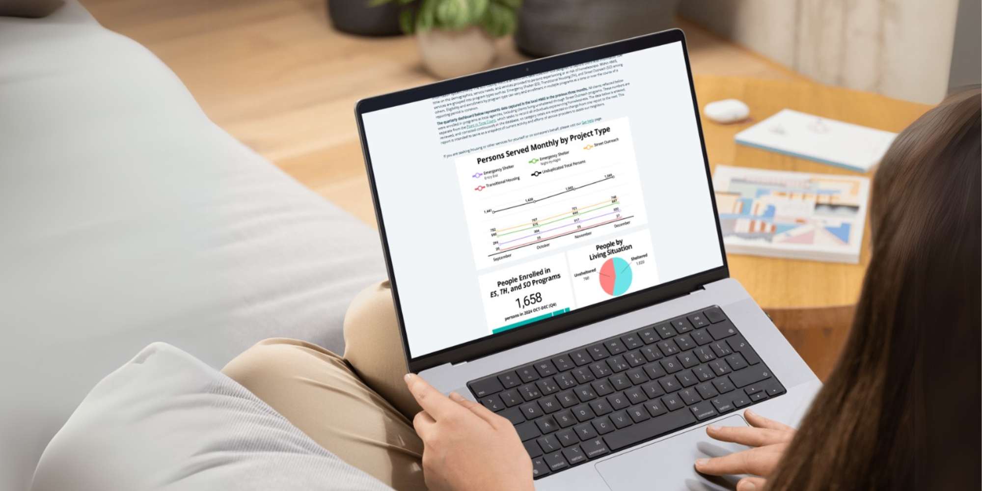 A person with long hair looking at the Quarterly Homelessness Database Dashboard on a laptop computer screen.