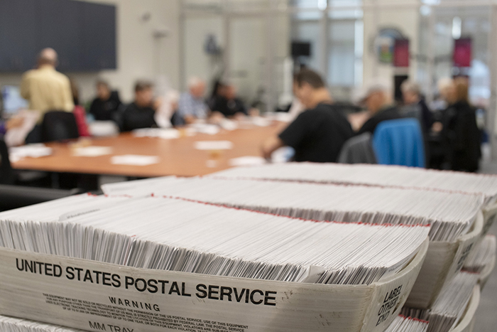 Vote-by-mail envelopes bundled in stacks of 50 and bound by rubber bands, as seen from above