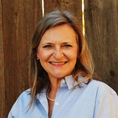 Image of Jennifer Kinnear in a light blue shirt standing in front of a wodden fence