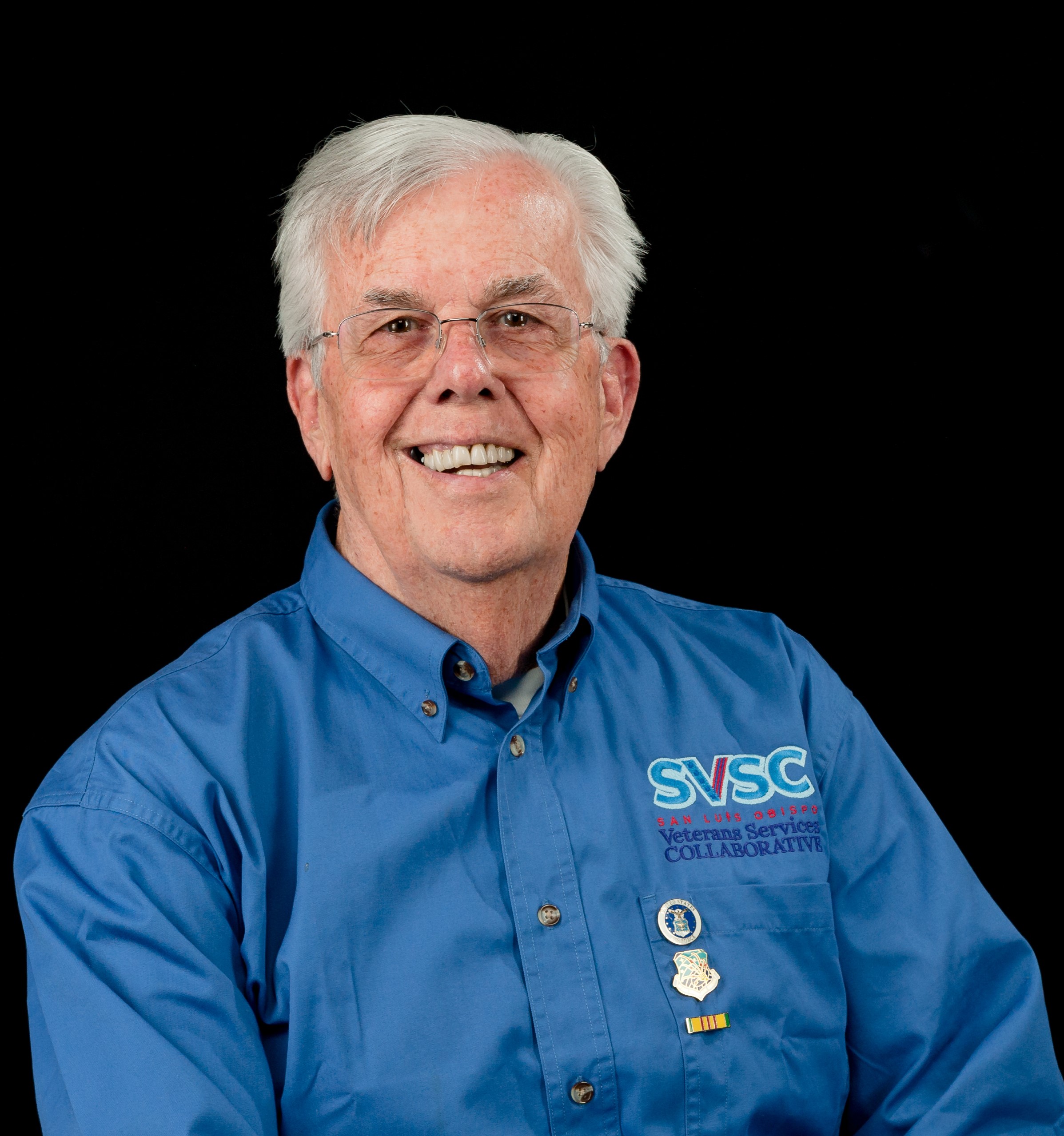 Photo of Paul Worsham wearing a blue shirt with the letters SVSC written on it in light blue. He is sitting in front of a black screen.