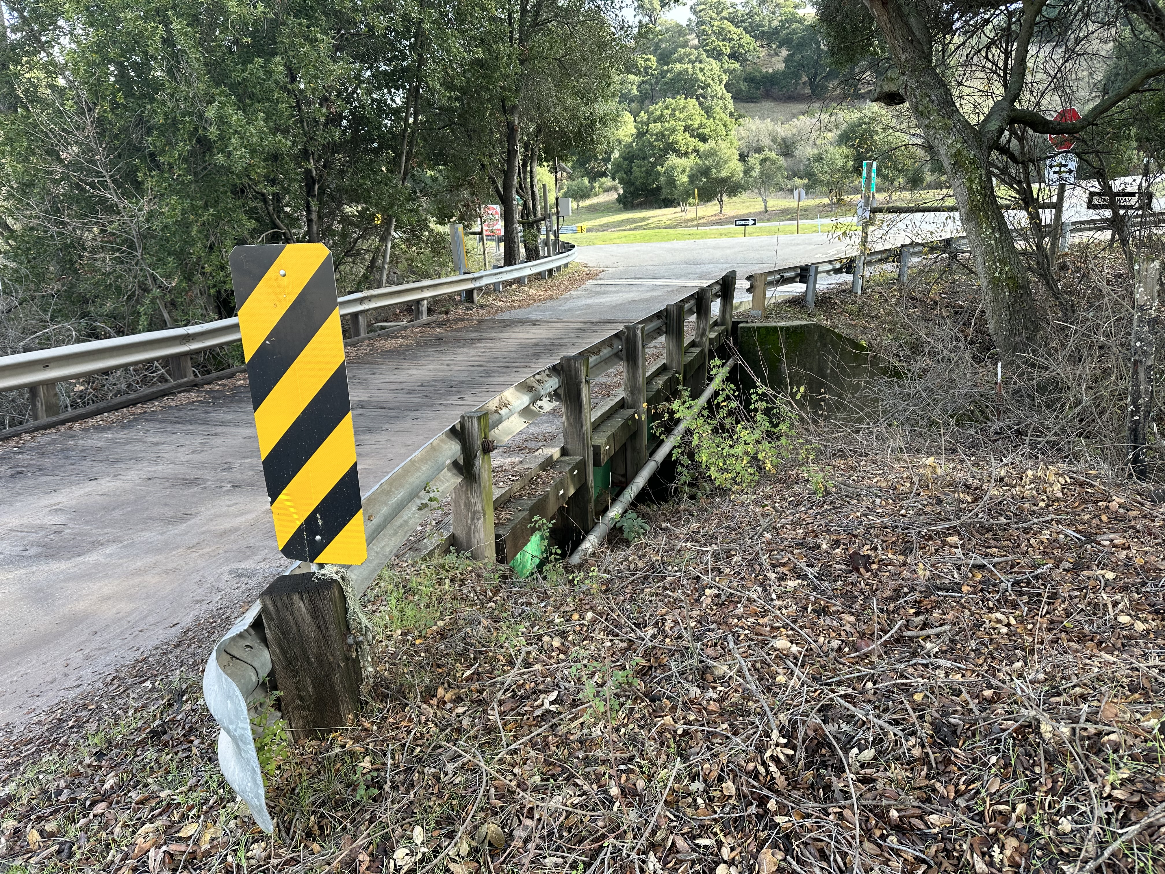 Low bridge over the creek with a yellow caution sign. 