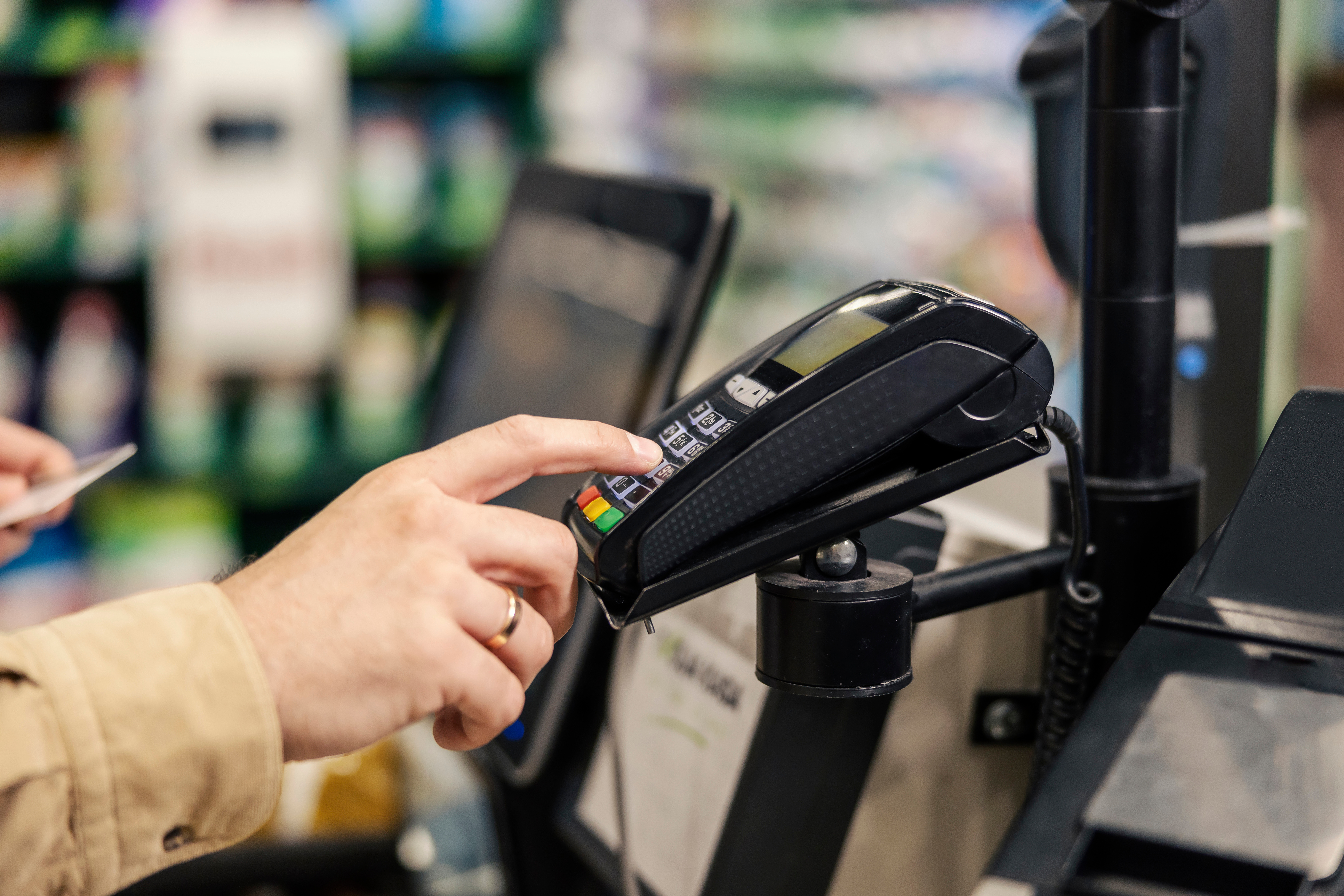 Man's hand putting in numbers on a credit card pin pad